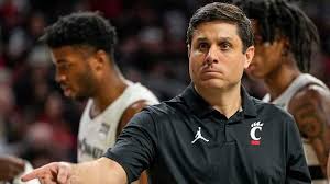 "Cincinnati Bearcats coach strategizes during a tense basketball game moment."