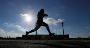 "Silhouetted athlete training at Panther Field during sunny day, demonstrating speed and agility."