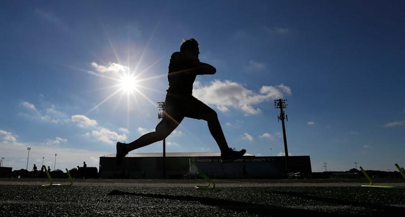 "Silhouetted athlete training at Panther Field during sunny day, demonstrating speed and agility."