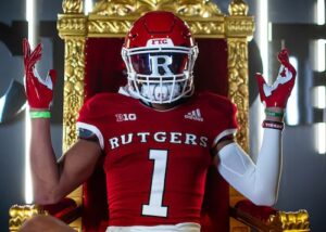 "Rutgers Scarlet Knights player in number 1 jersey poses regally on a throne during a photo shoot event"