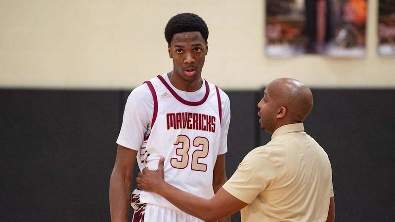 "Mavericks basketball player number 32 receives guidance from coach during a strategy discussion in the gym"