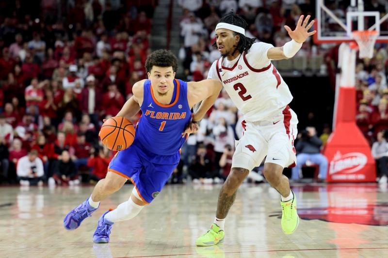 "Clayton dribbles past a defender in a Florida Gators vs. Arkansas Razorbacks basketball game, highlighting his NBA draft projection."