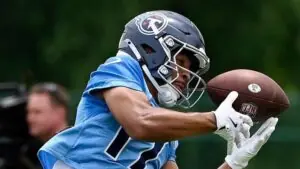 "Titans rookie receiver practices catching drills at Titans minicamp, showcasing intense focus and skill."